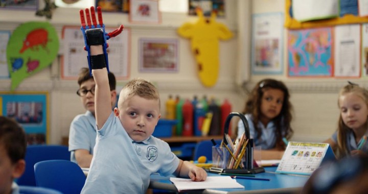 Child raising prosthetic hand in class